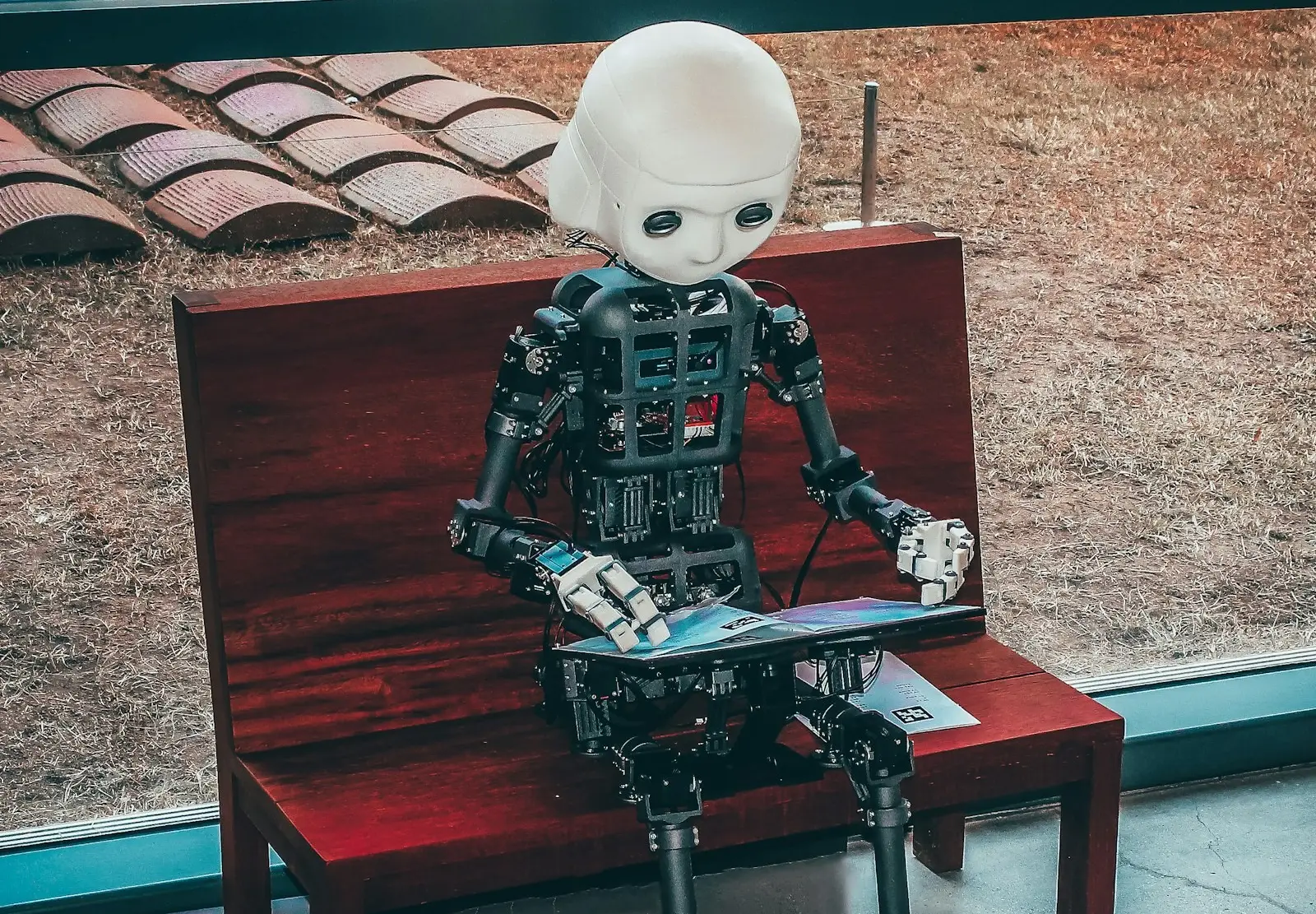 The Three-Lens Assessment, Explained – Progreziv | Progreziv Humanoid robot using a laptop, representing the methodical three-lens assessment used to evaluate AI readiness and operating model fitness